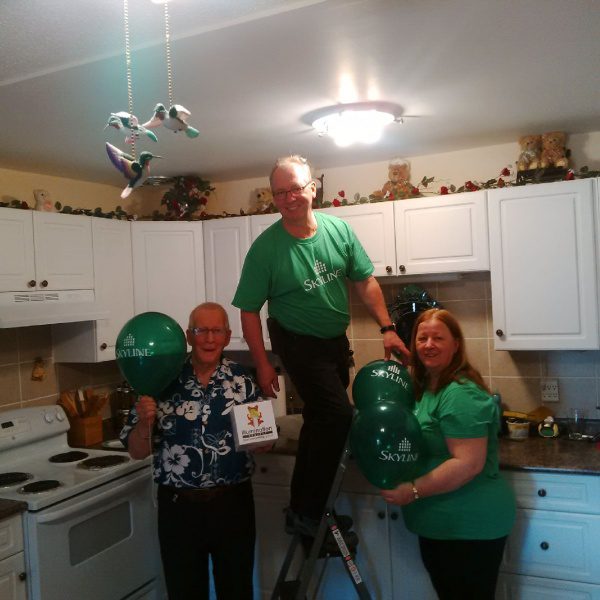 A resident manager installs a CFL light bulb, while the resident smiles